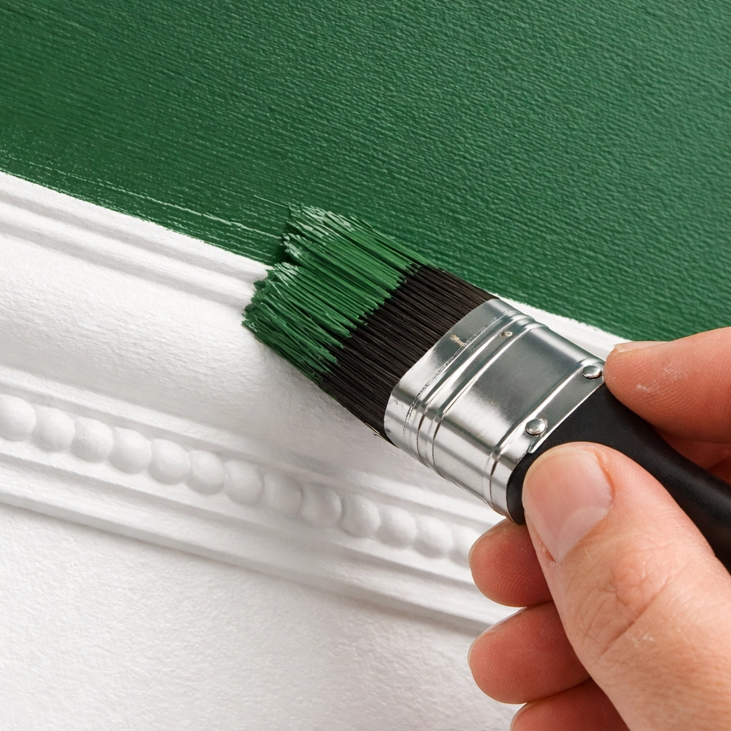 Professional painter applying forest green paint to a ceiling edge with crisp white coving.