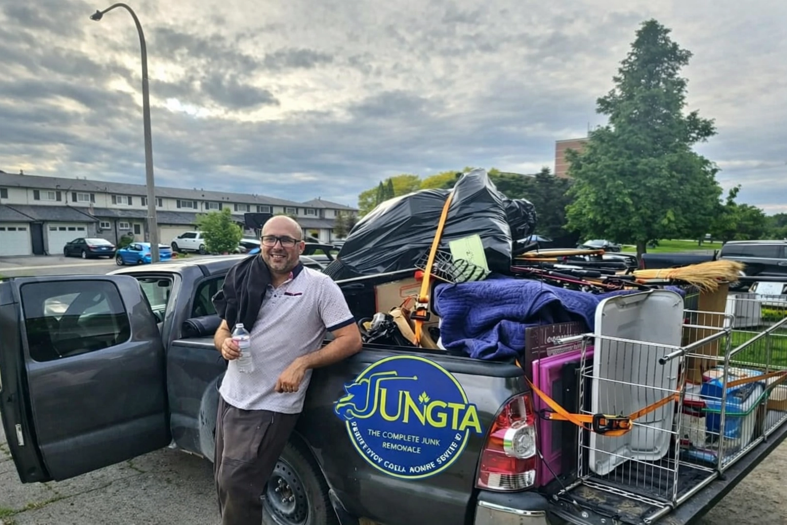 Junk GTA crew member standing beside a pickup truck loaded with various junk items prepare for responsible disposal and recycling