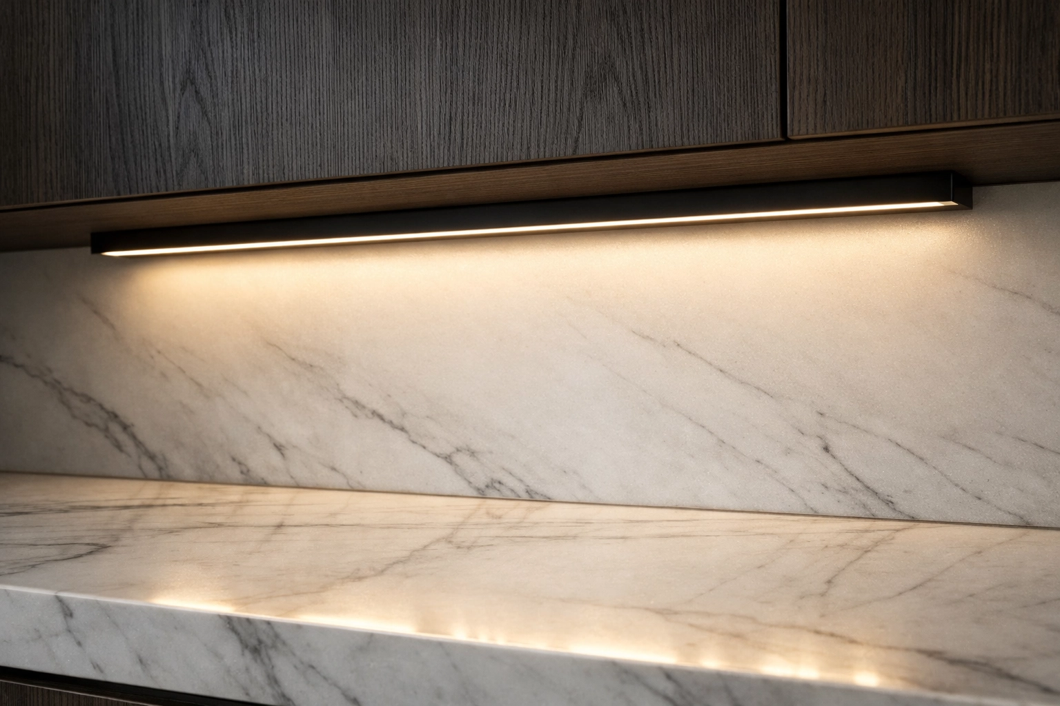 Matte black aluminum LED channel providing diffused under cabinet lighting on a white marble kitchen countertop.