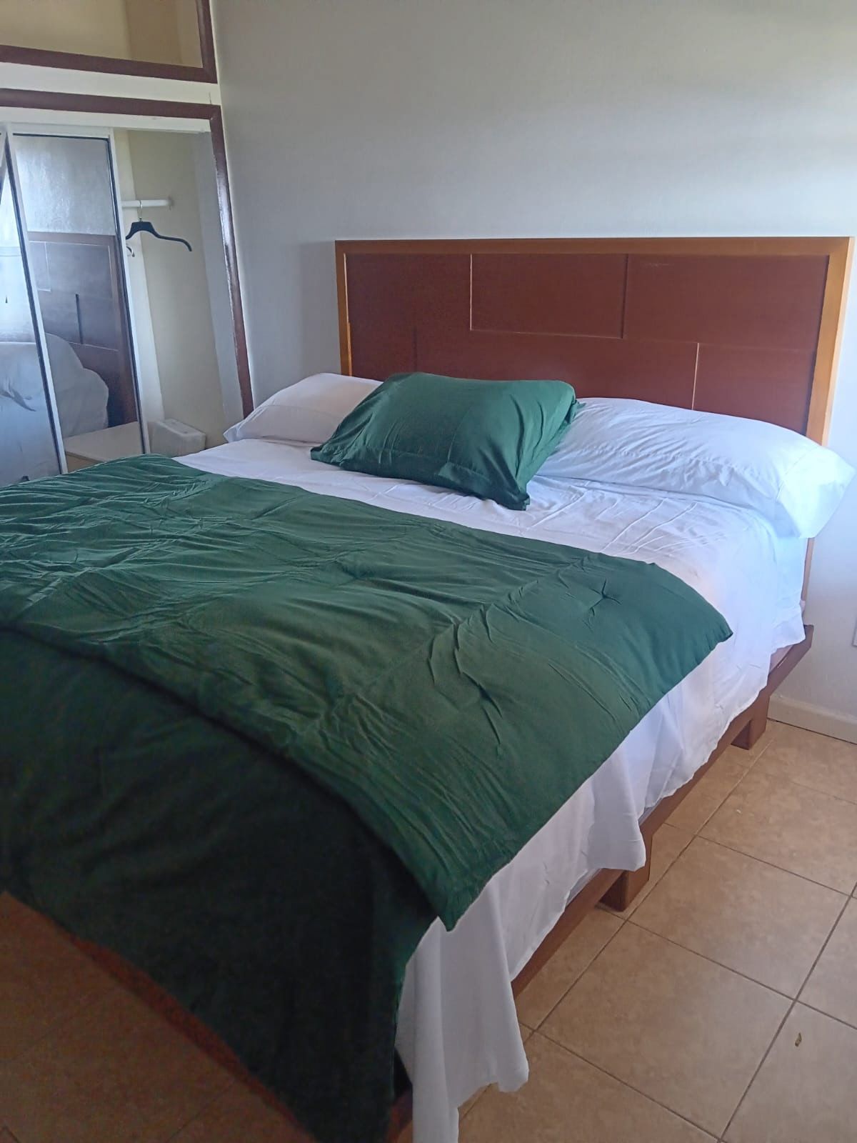Spacious guest room with large bed and deep green comforter