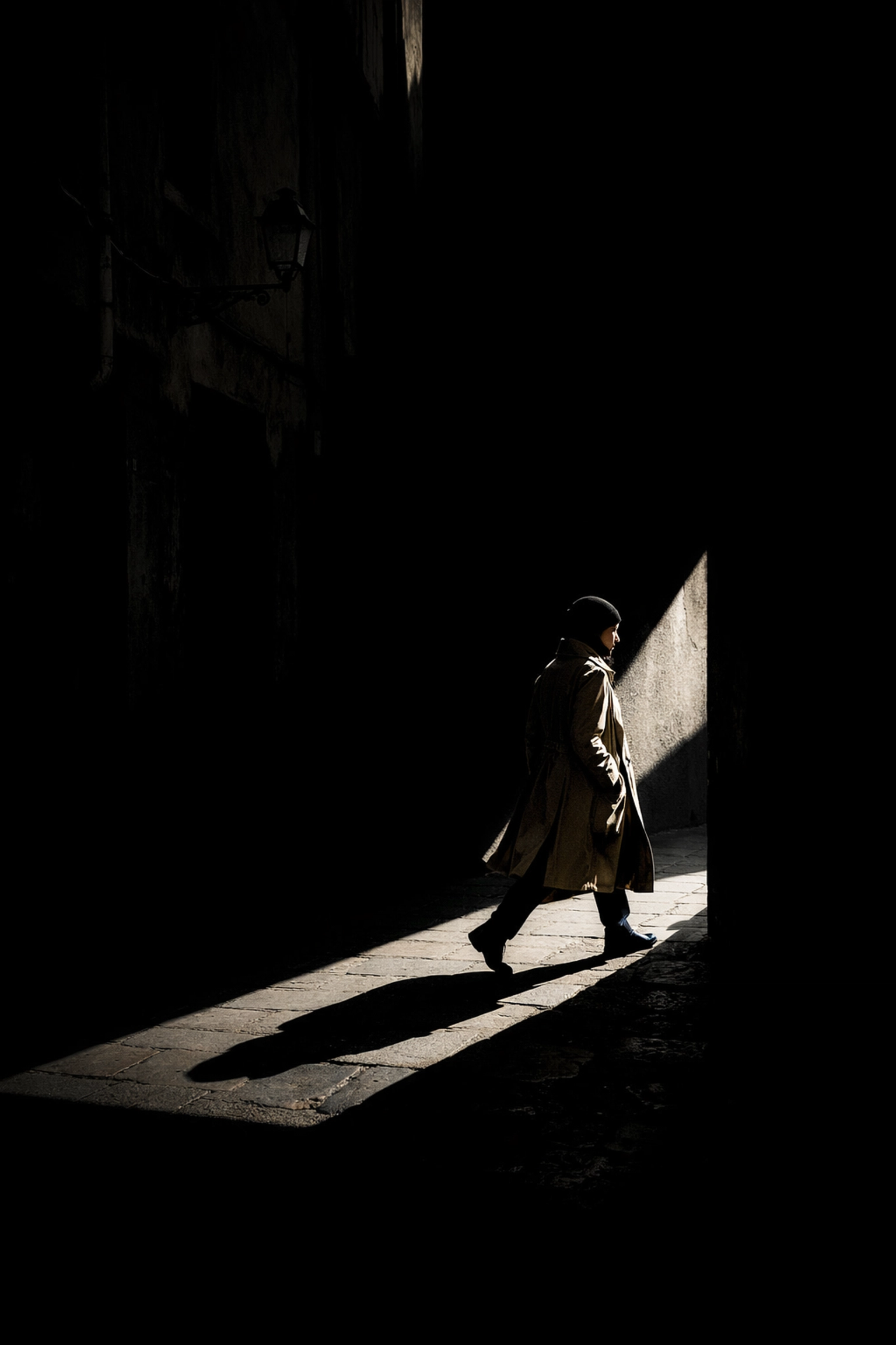 Dramatic street photography shadows and light in an alleyway creating high-contrast geometric shapes.