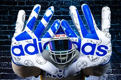 A professional portrait of a football player showcasing Falcons Adidas gloves against a dark background.