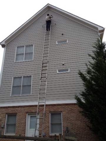 A Southern Wildlife Management technician sealing a high gable vent