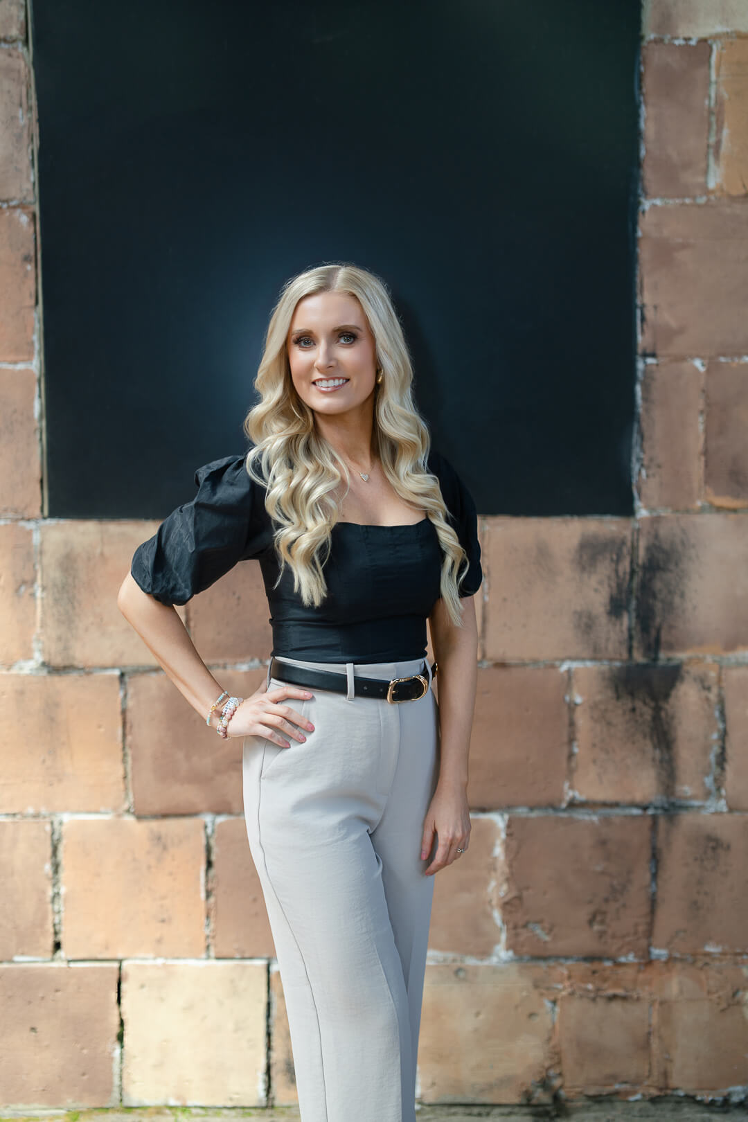 Confident entrepreneur posing against a textured brick wall
