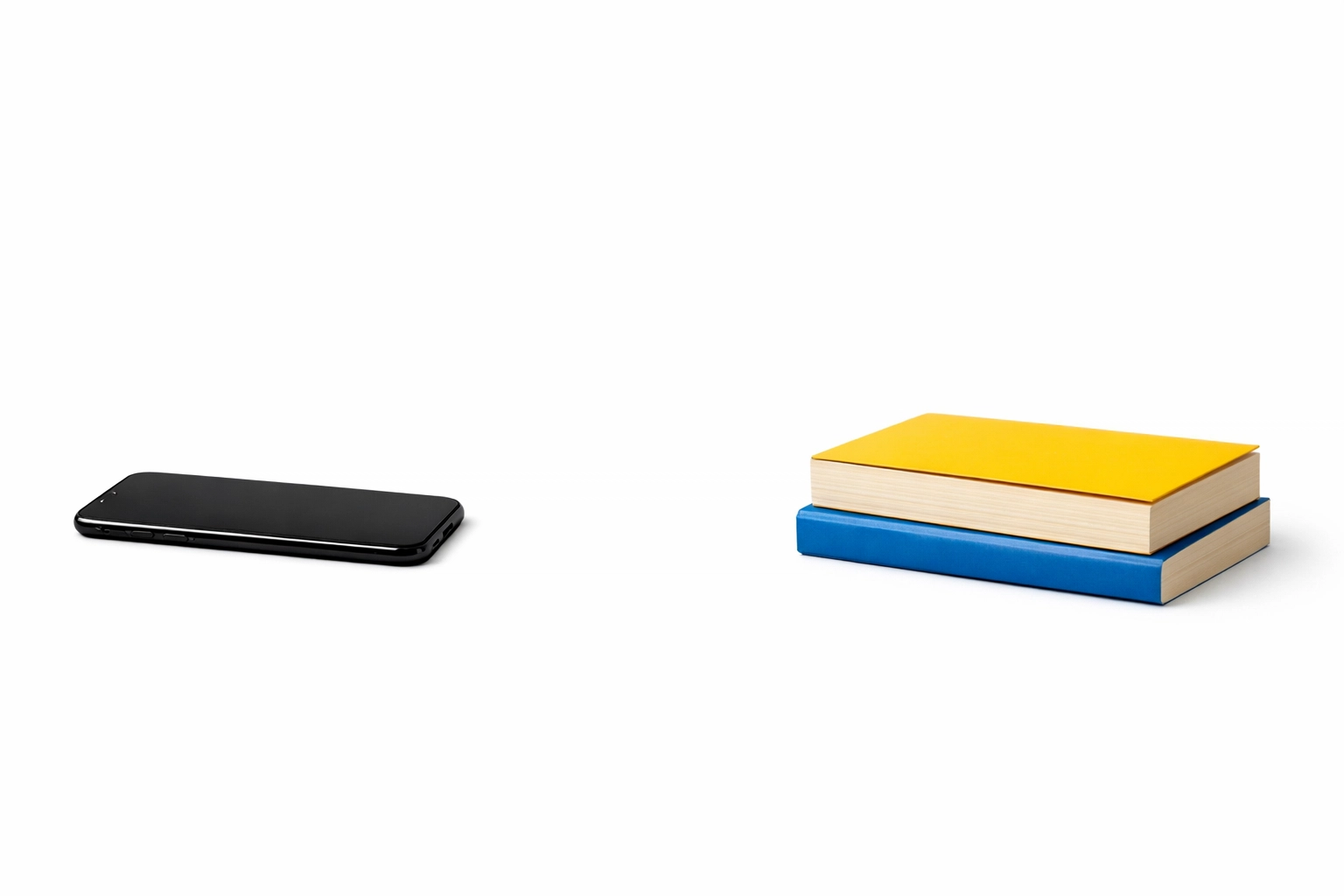 A smartphone placed face down next to a stack of books to show reducing distractions for better reading focus.