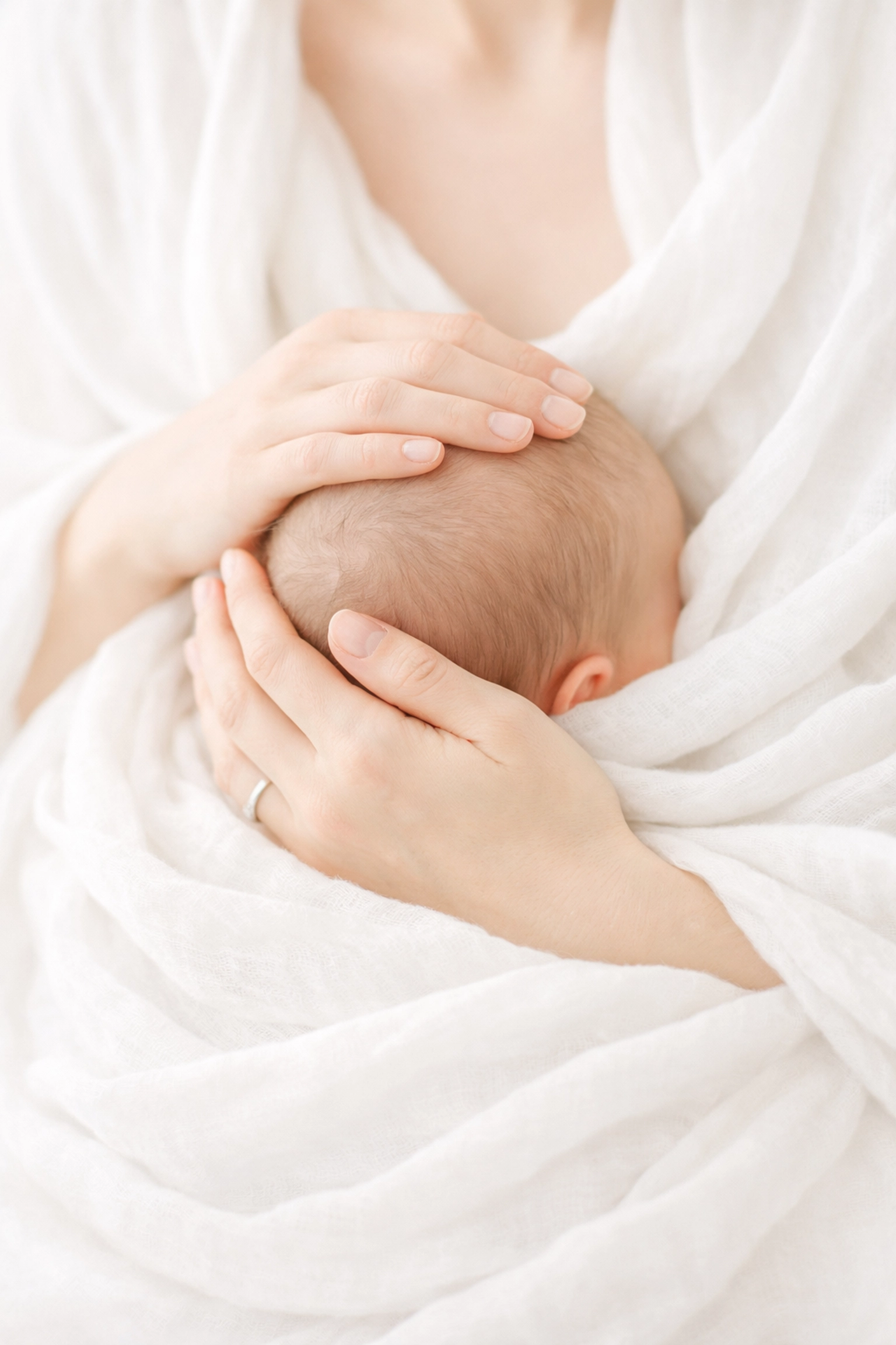 Intimate skin-to-skin newborn portrait with mother's hands in a bright Northern Beaches studio.