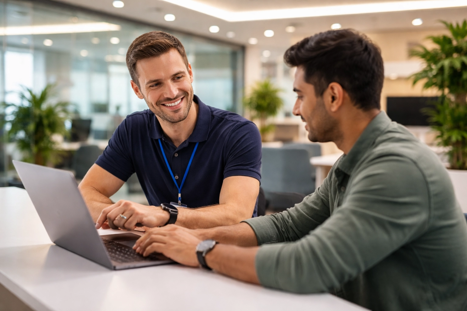 IT specialist assists employee with laptop in tech lounge, highlighting service mapping in Employee Center.